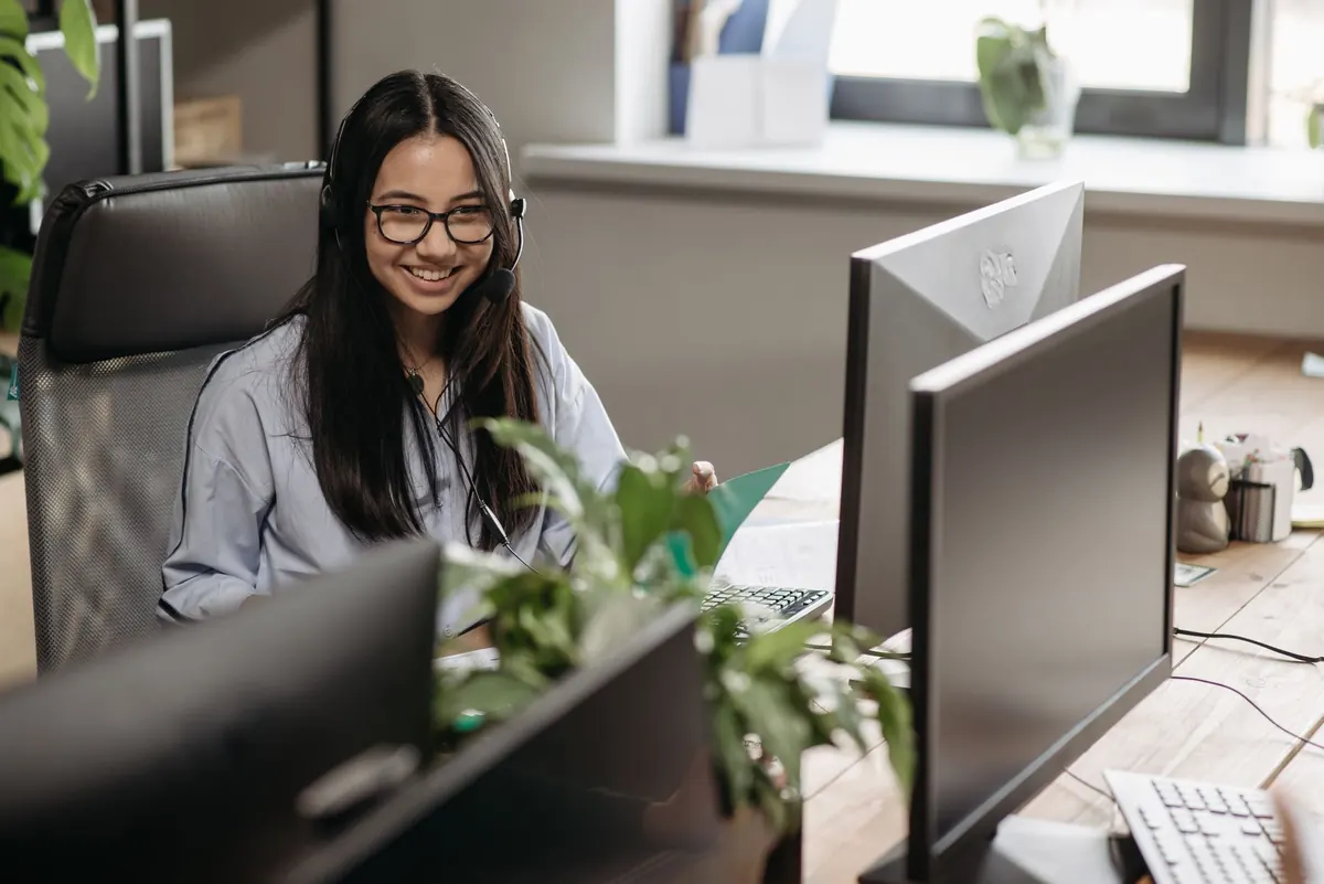 Atendente de fone de ouvido sorrindo em frente ao computador
