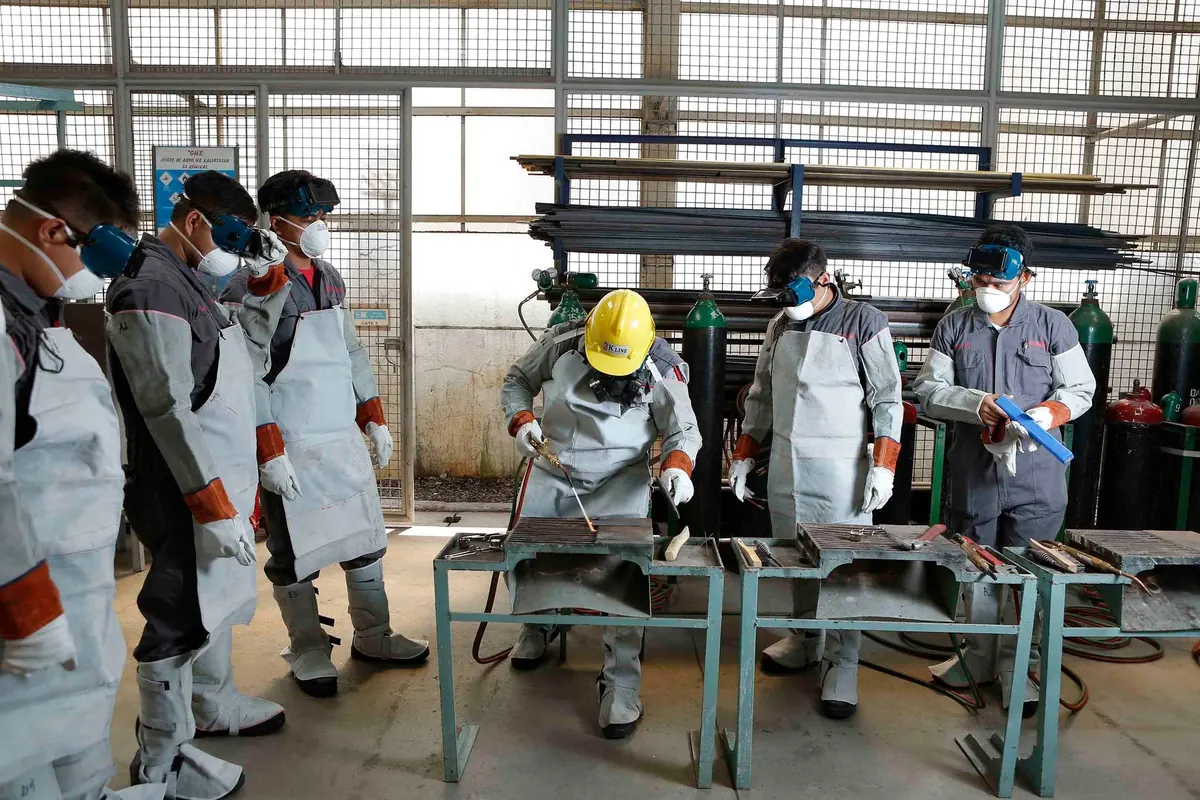 Grupo de trabalhadores com equipamentos de proteção em um treinamento prático
